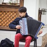 man playing blue accordion during daytime