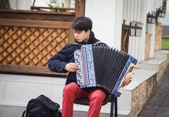 man playing blue accordion during daytime